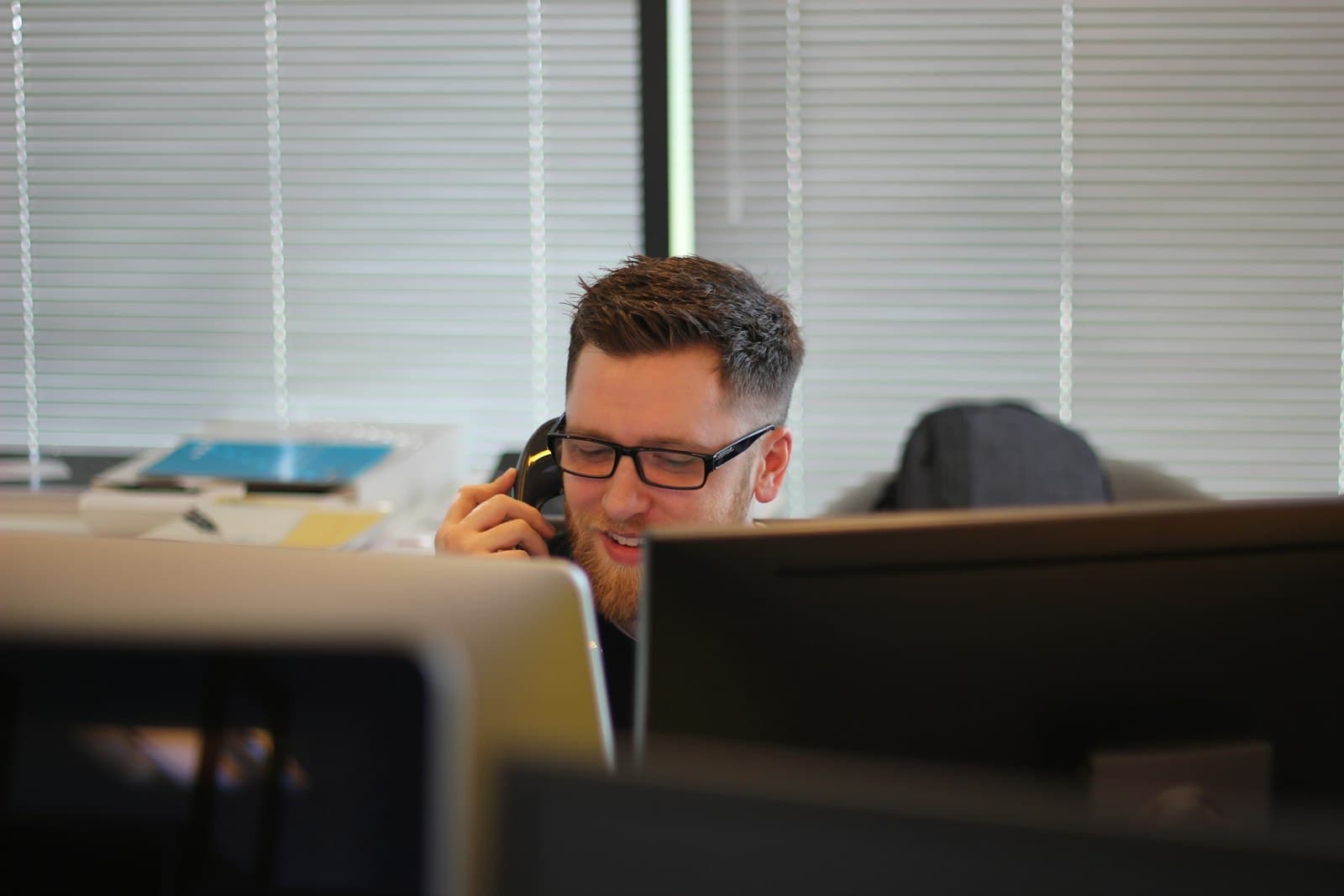 A person answering a desk phone.
